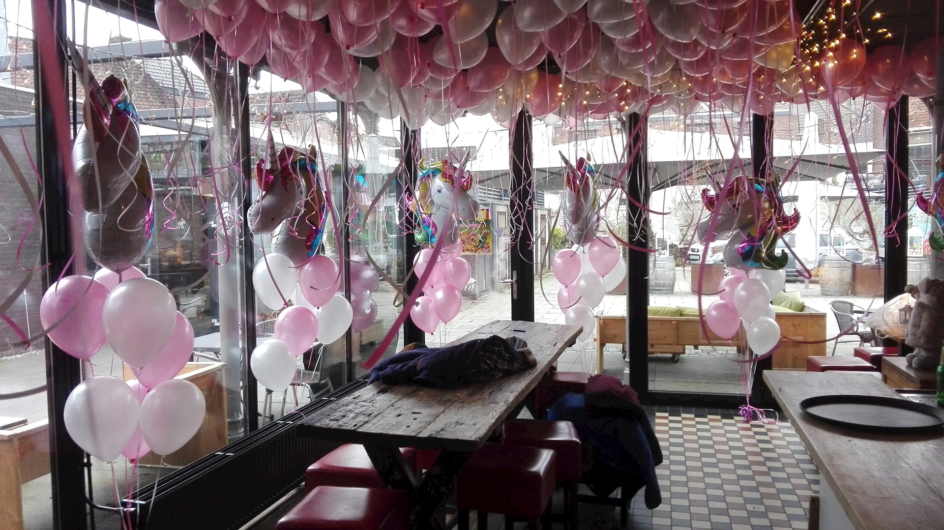 kinderfeest met plafond vol helium ballonnen en trossen met op top Unicorn ofwel eenhoorn